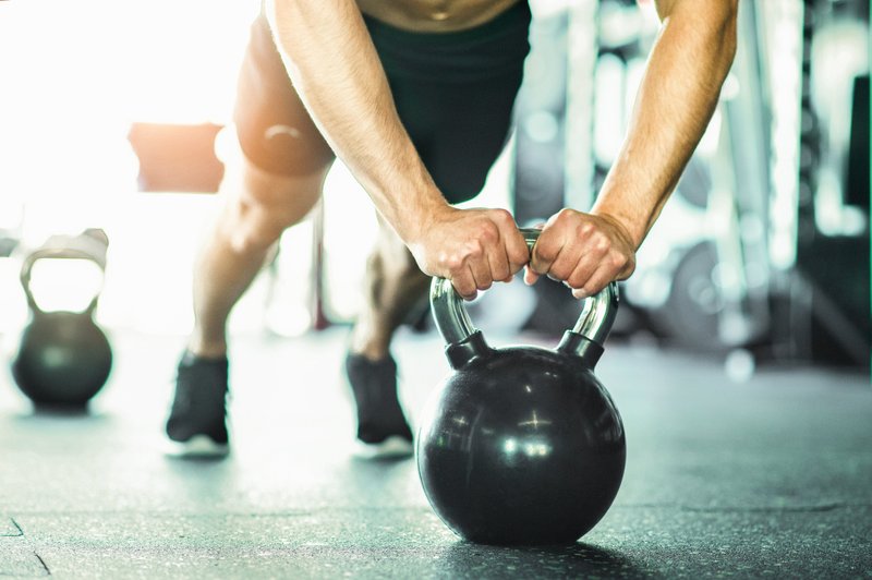 Mann macht Liegestütze auf der Kettlebell